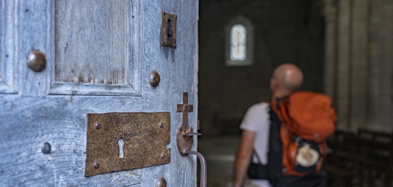 Un randonner sur le Chemin de Compostelle entre dans une église